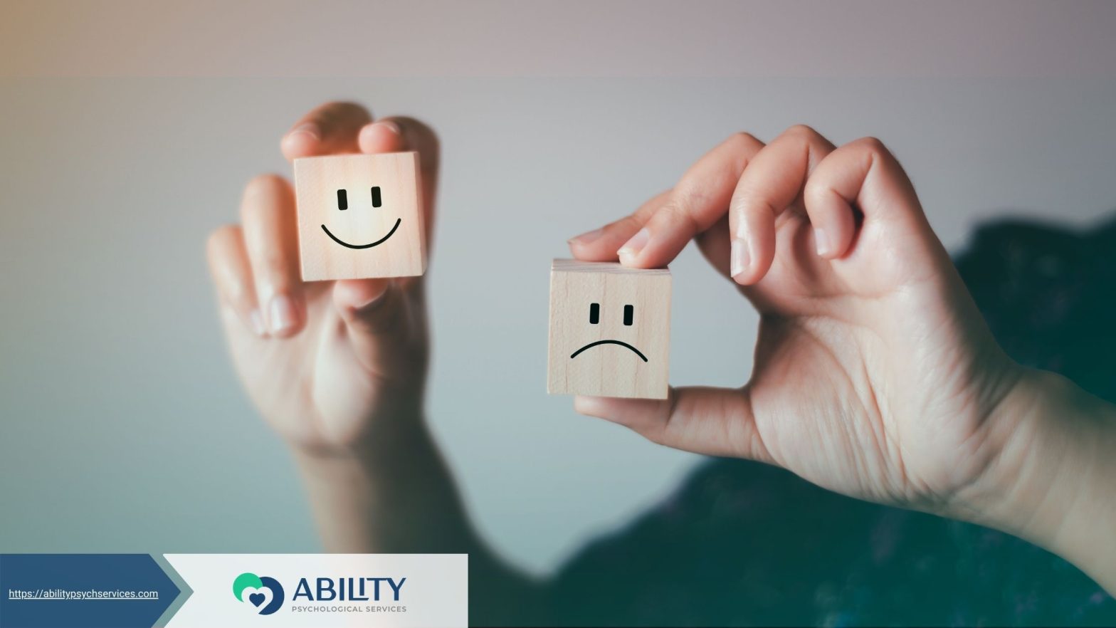 Hands holding blocks with happy and sad faces, symbolizing mental health.