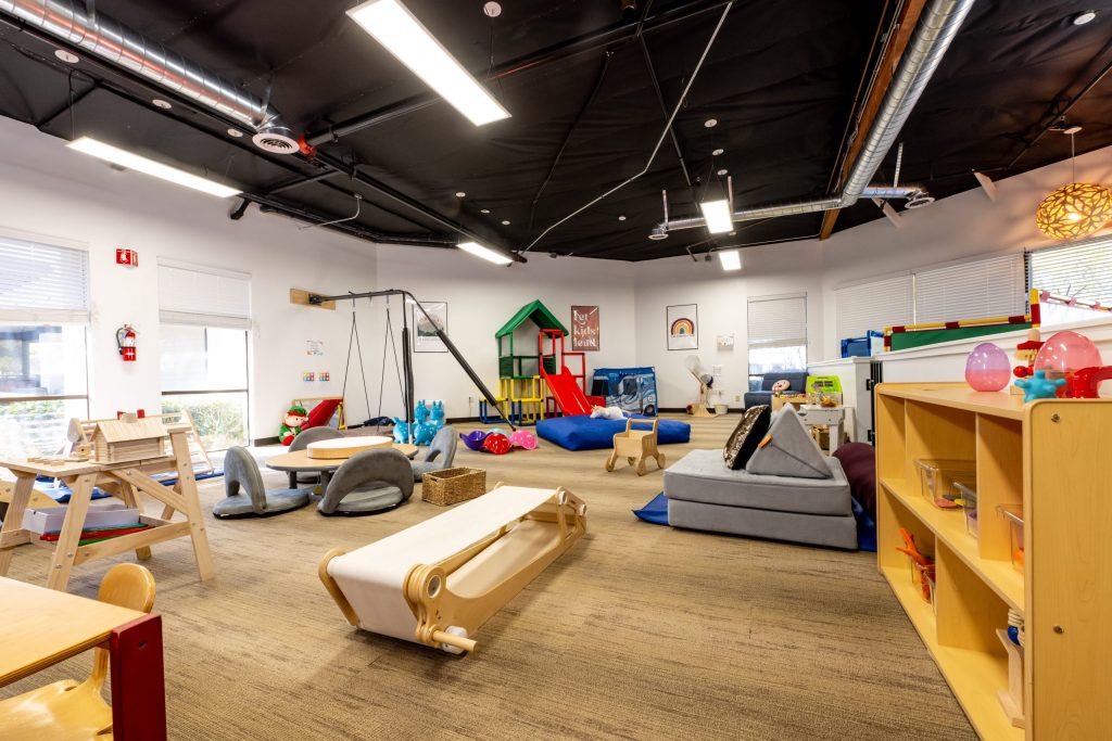 Bright, spacious indoor sensory playroom with swings, climbing structures, and soft mats—ideal for engaging children with ADHD.