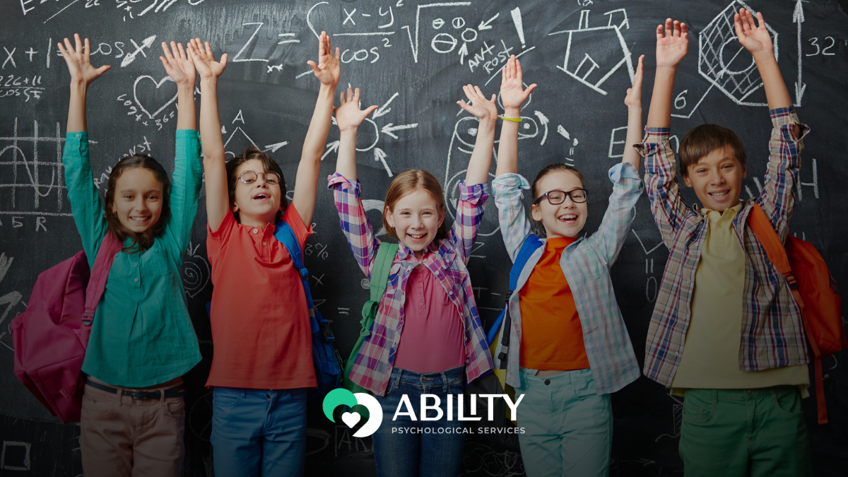 Five smiling schoolchildren with backpacks raise their hands in front of a chalkboard, symbolizing advocacy and ADHD school support in Oakland.